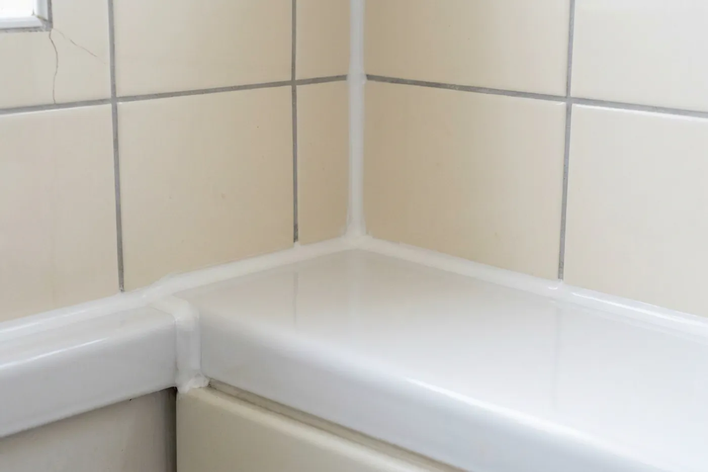 The same bath joint from the same position after resealing, with a clean, evenly tooled white silicone bead